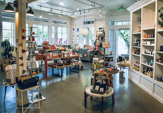 Interior of a store with shelves, tables, and products on a concrete floor.
